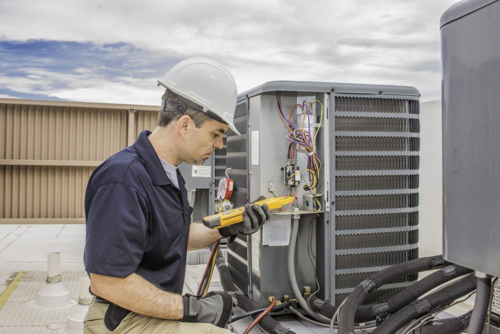 technician performing preventative maintenance on a air conditioning unit